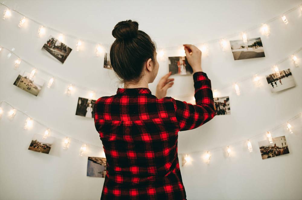 a woman hanging her photographs into the wall with led lights
