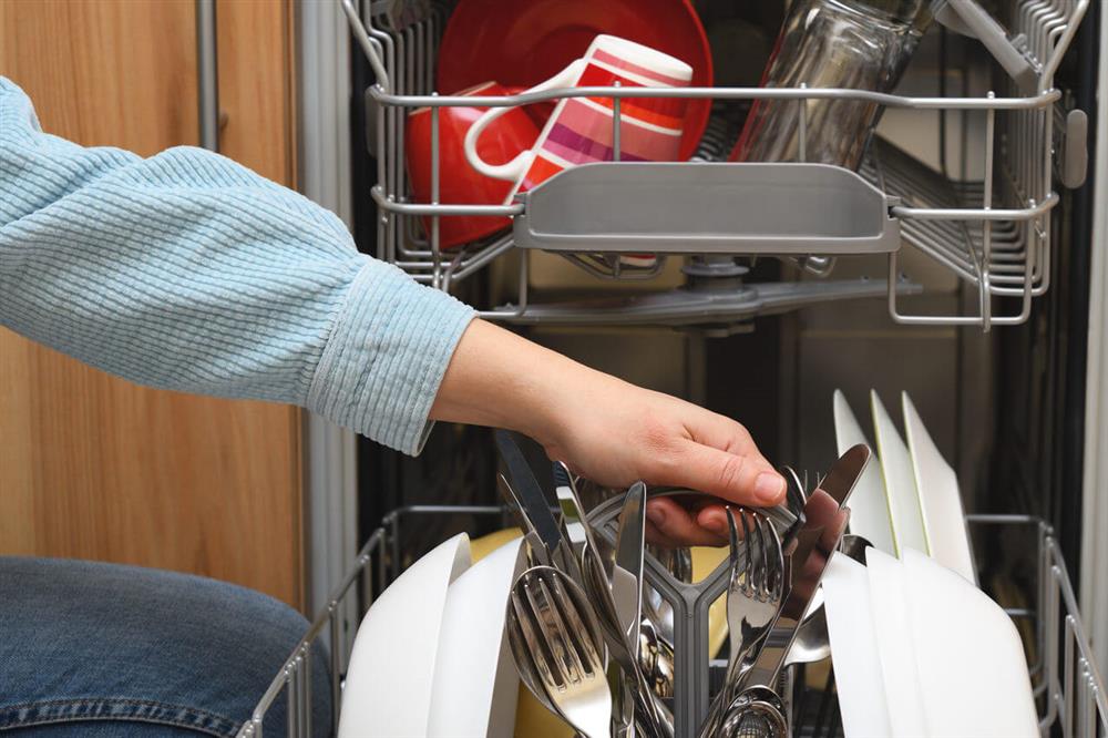 female taking clean dishes out of dishwasher