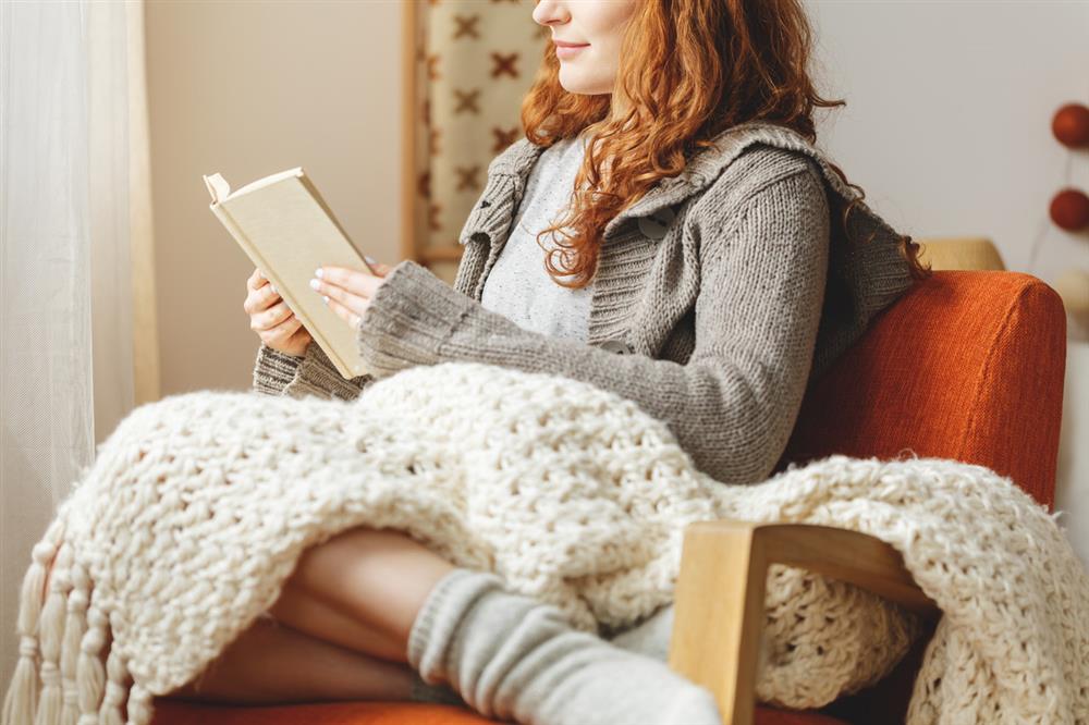 battaniye ile kitap okuyan kadın