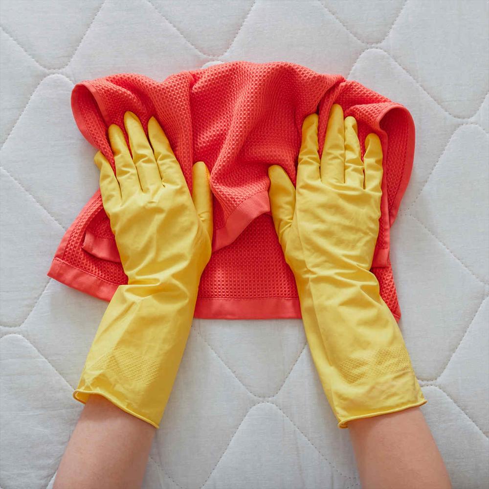An employee with yellow gloves cleaning the stains on the mattress