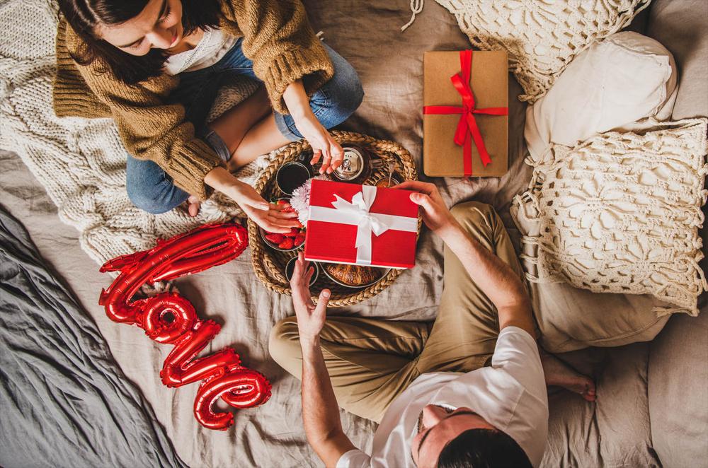 couple sitting in bed and giving presents for valentine's day